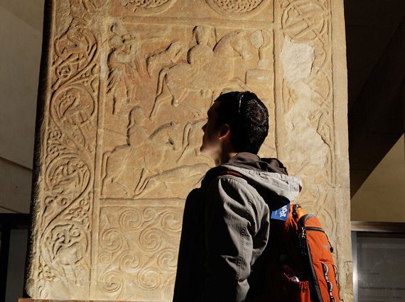 A person examining a Pictish stone carving in a museum